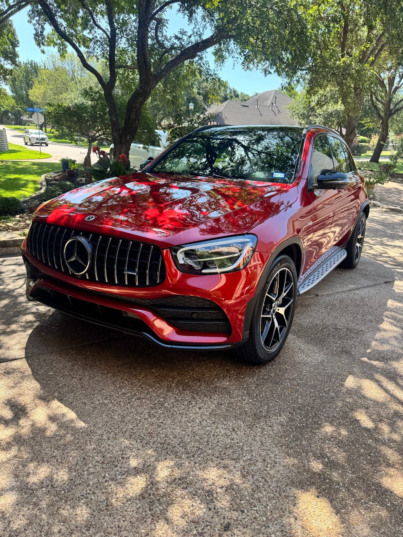 A detailed red Mercedes-AMG GLC, front three-quarter view under trees