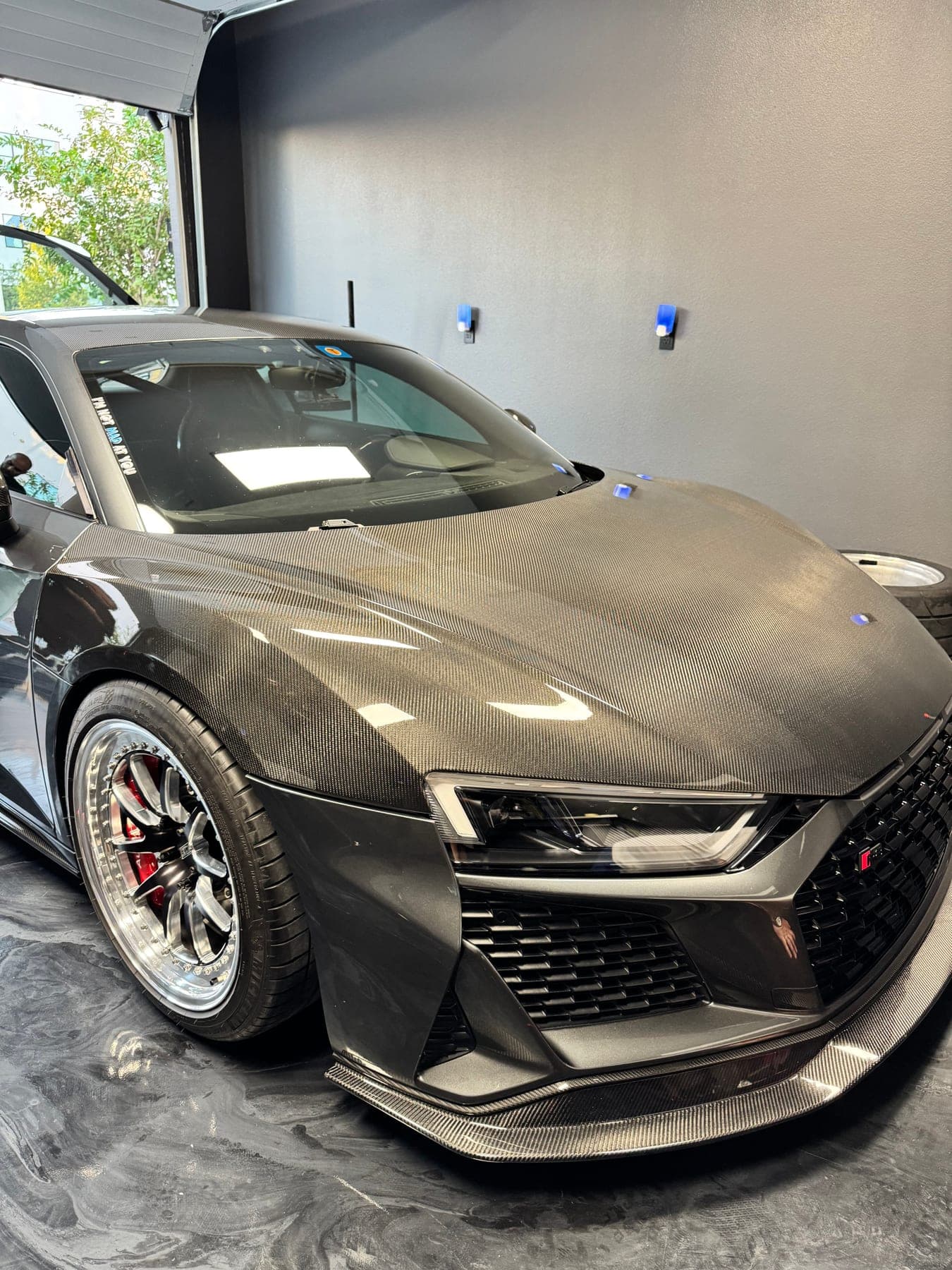 A carbon-fiber widebody Audi R8, low front three-quarter view in a private garage