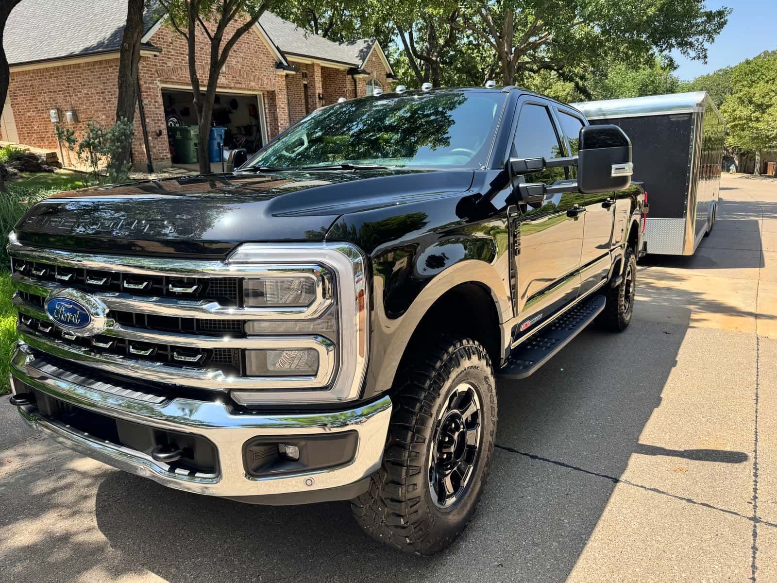 A detailed black Ford F-350 Super Duty towing an enclosed trailer, front three-quarter view