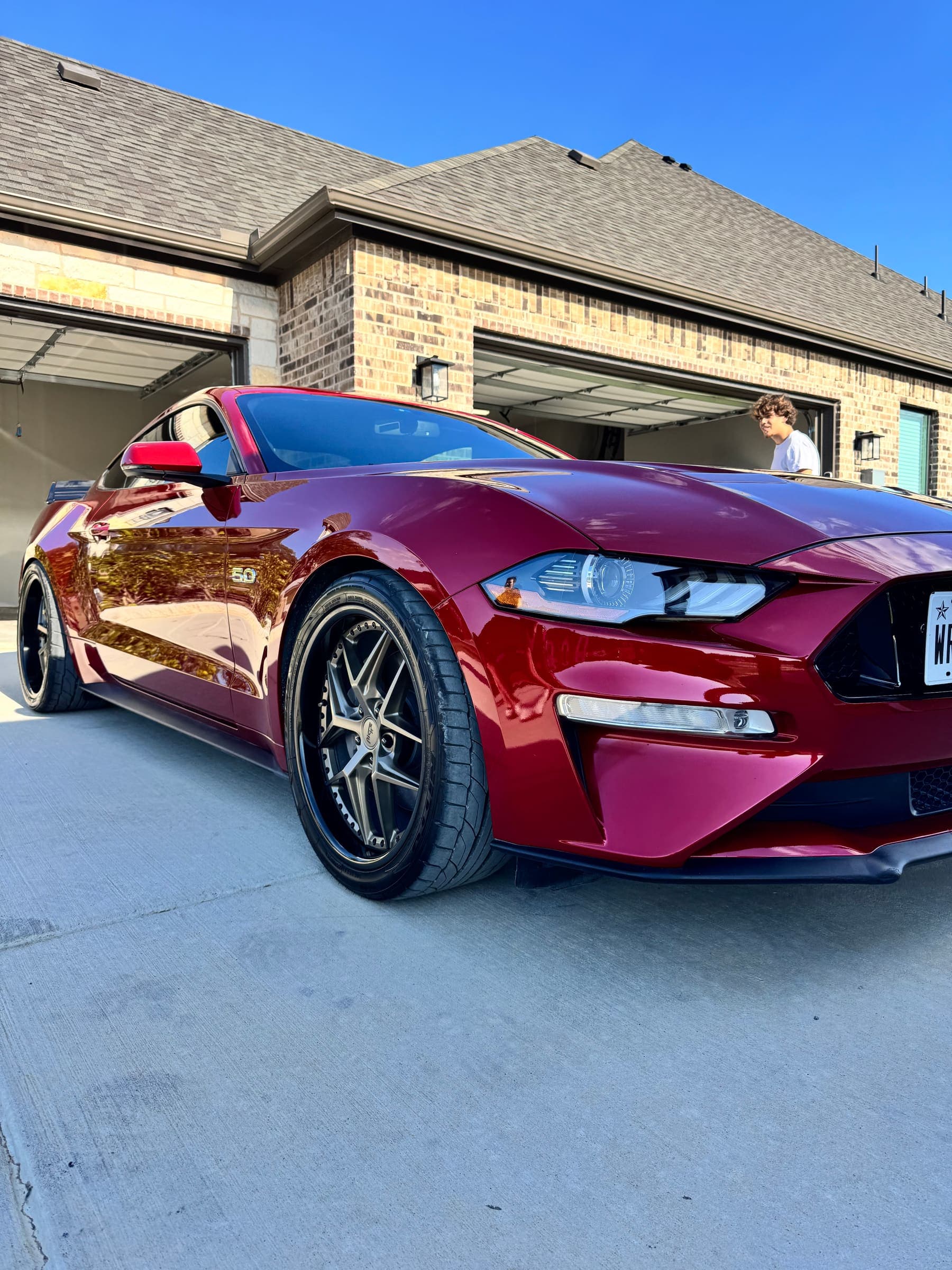 A detailed dark red Ford Mustang GT, three-quarter front view in a driveway