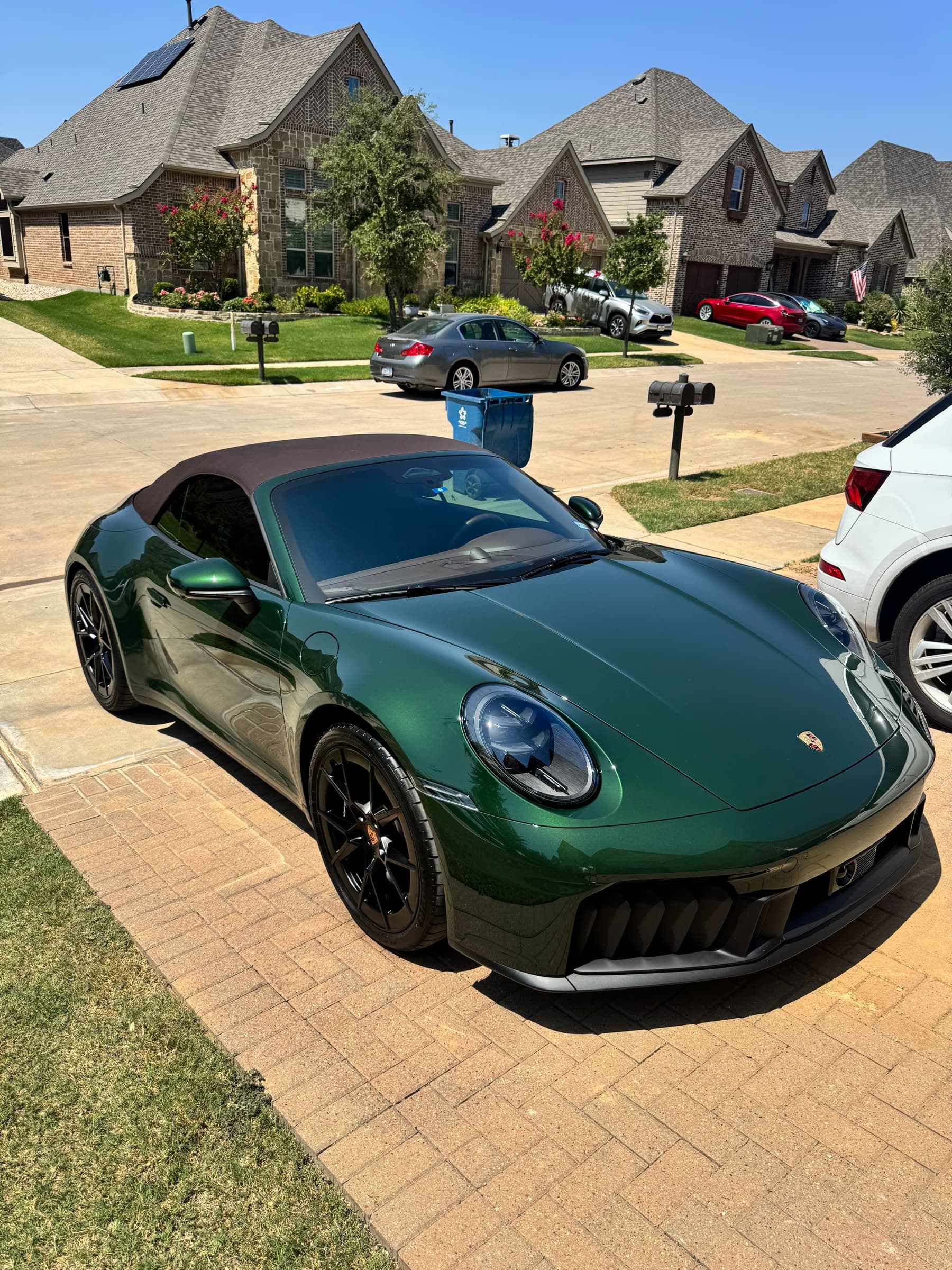 A detailed green Porsche 911 Cabriolet, three-quarter front view in a driveway